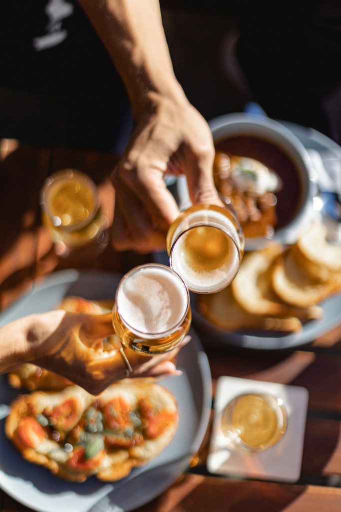 Friends toasting beers over food outdoors