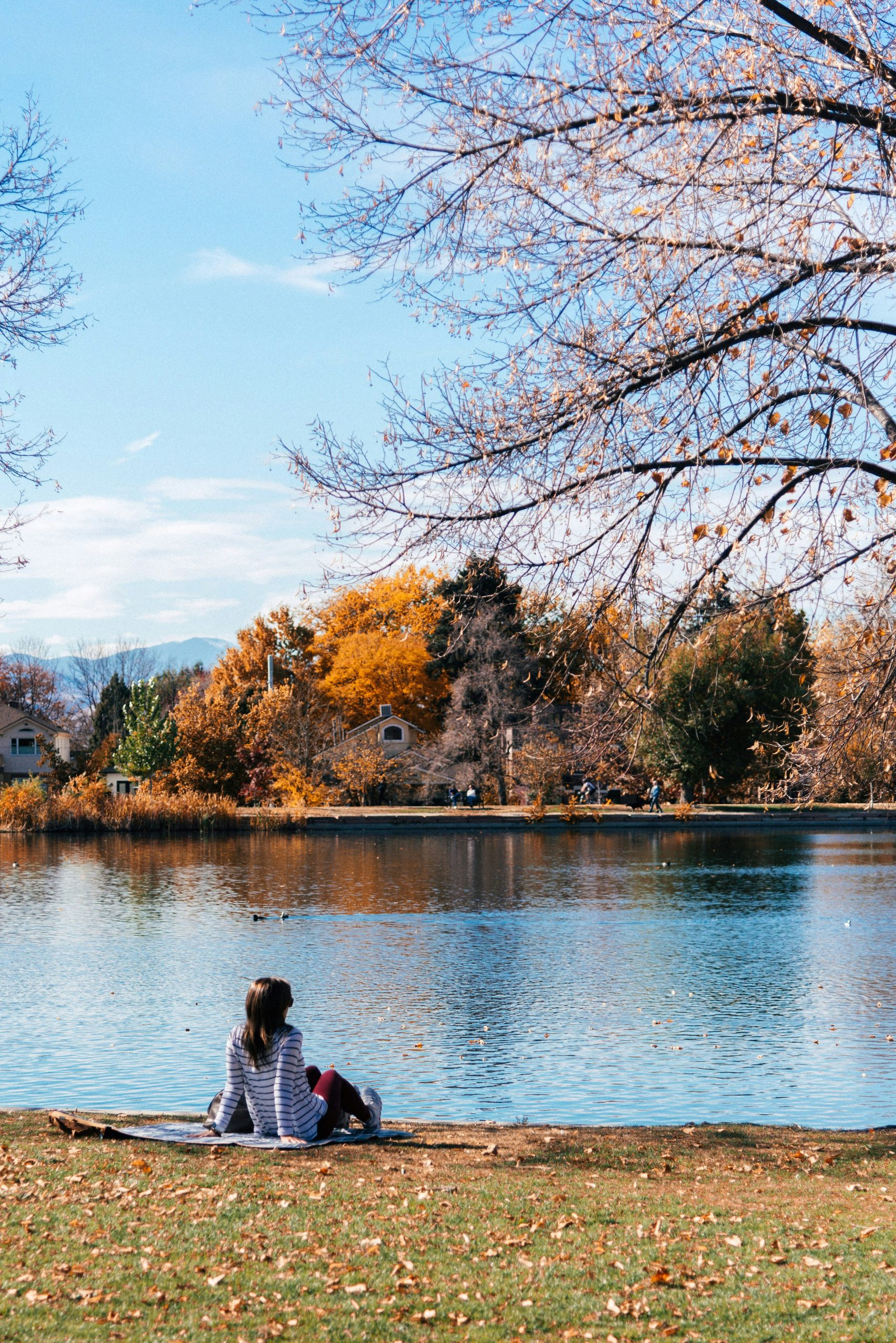 Person relaxing by a calm autumn lake