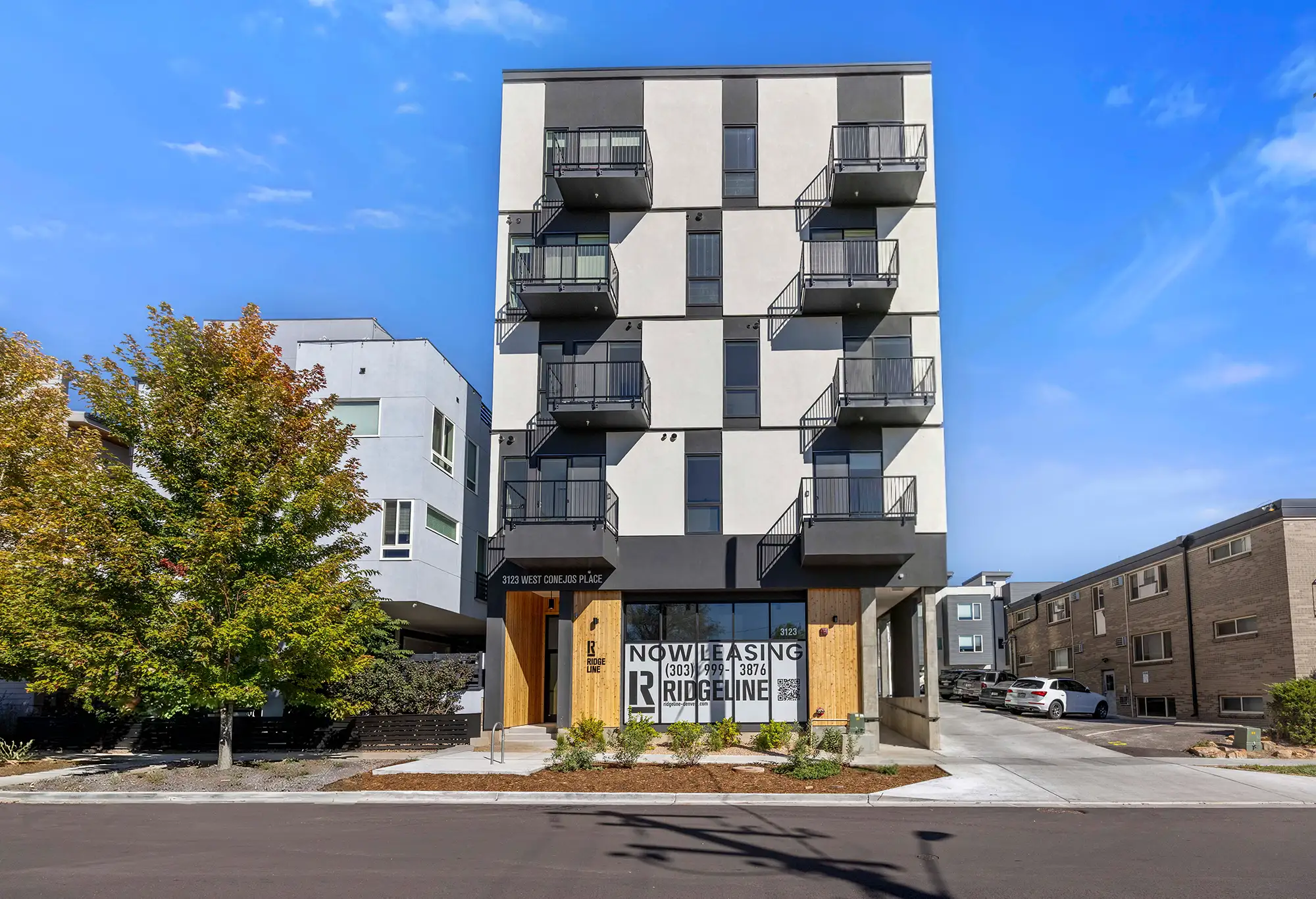 Modern apartment building with balconies and leasing sign
